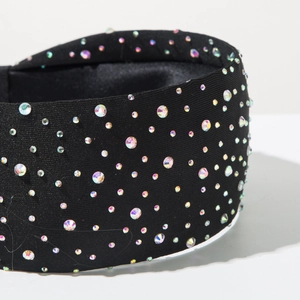 Detailed close-up of wide black headband with colorful rhinestones on knit fabric
