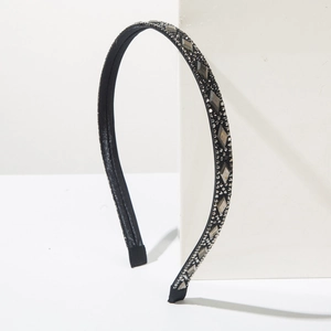 Detail of elegant black headband with crystals and pearls on minimalist white stone base