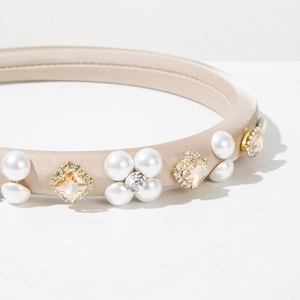 Detailed close-up of a champagne satin headband with floral pearls and square rhinestones