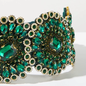 Close-up of luxury Baroque wide headband with emerald green crystals and gold rhinestones
