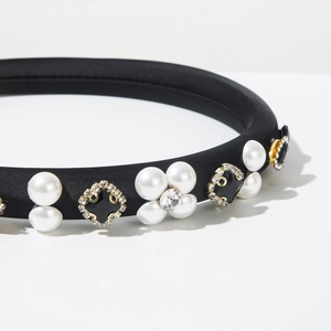 Detailed close-up of a black fabric headband featuring pearl flowers and rhinestone gems