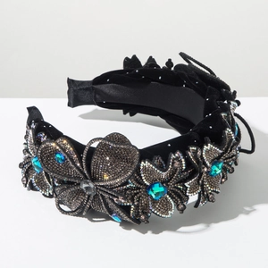 Macro shot of velvet headband with crystal floral petals and emerald gemstone
