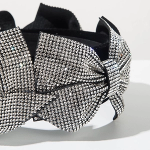 Close-up of black velvet headband featuring hand-set crystals in a 3D bow design