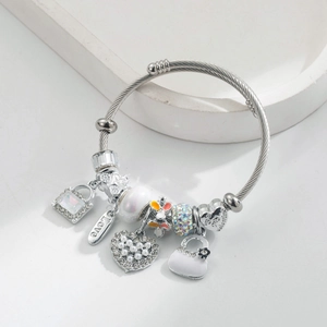 Bracelet en fil d'acier argenté avec breloques cœur et perles sur support en marbre