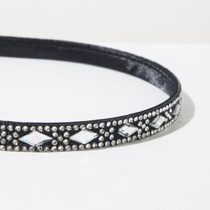 Macro shot of black headband featuring intricate silver rhinestone patterns and velvet base