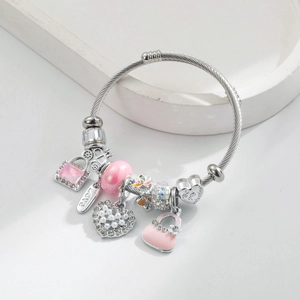 Détail d'un bracelet perlé argenté avec breloque cœur rose et pendentif gravé