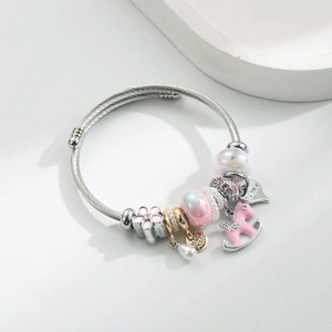 Detail of silver woven bracelet with pink charms, pearl, pony, and Gemini heart tag