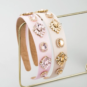 Baroque style wide headband with pink and beige crystals on a golden display stand