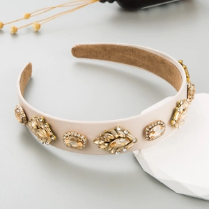 Close-up of champagne satin headband with intricate rhinestone and gemstone embellishments