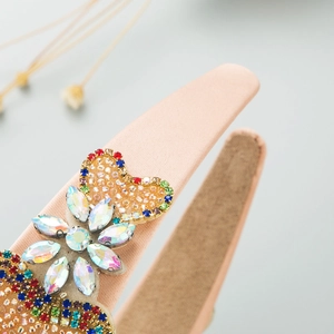 Macro view of a pink satin headband with colorful rhinestones and floral hand-beaded details