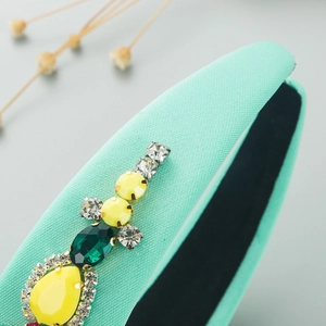 Detailed macro view of mint green headband featuring yellow and green crystal rhinestones