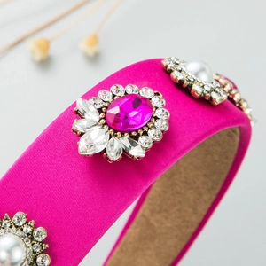 Detail of a wide fuchsia satin headband with large oval gems and imitation pearls