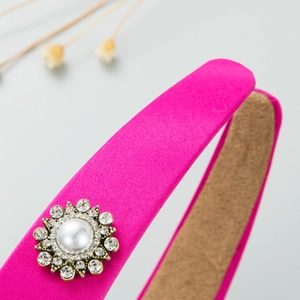 Detail of rose pink satin headband featuring a pearl and rhinestone vintage gold setting