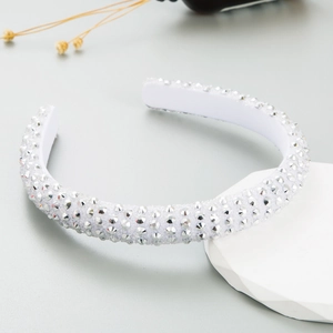 Gepolstertes weißes Stirnband mit glitzernden Strasssteinen auf einem minimalistischen Ständer