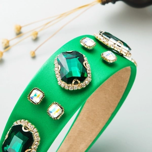 Close-up of green emerald crystals and white stones on baroque satin wide headband