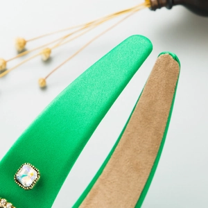 Detail of emerald green satin headband with square crystal embellishments and velvet lining