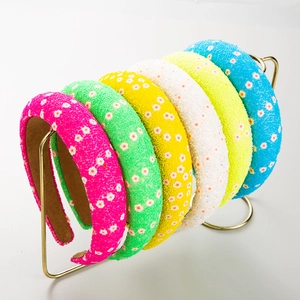 Detailed close-up of wide padded headbands with colorful floral patterns on a gold rack