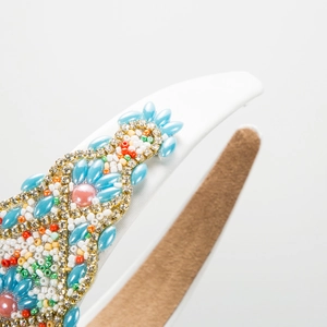 Detailed close-up of Baroque headband with colorful beads and sequins on white silk