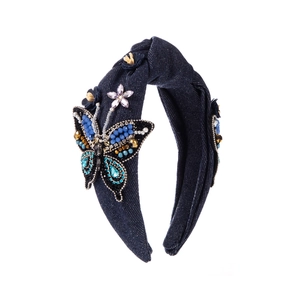 Détail d'un serre-tête en denim bleu avec papillon perlé à la main, strass et fleurs en tissu