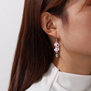 Detailed close-up of a pink game controller earring with crystal heart charm on a model