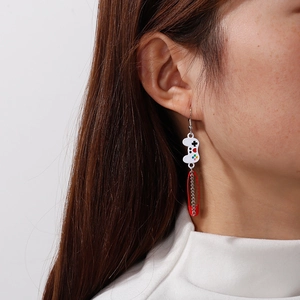 Detail of creative game controller earring with red safety pin and silver metal chain