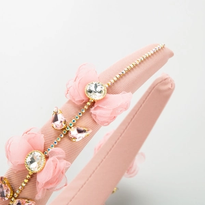 Détail d'un serre-tête en tissu rose avec nœud en tulle et strass brillants