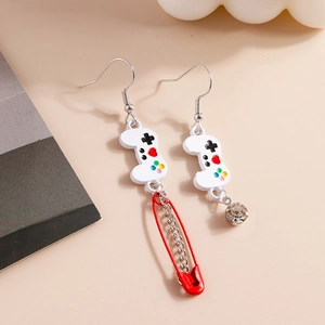 Macro detail of asymmetric game controller earrings with a red safety pin and gemstone