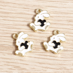 Close-up of three white rabbit alloy pendants with black hearts for DIY jewelry making
