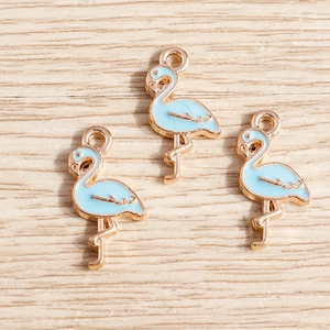 Detail of three light blue enamel flamingo charms with gold alloy plating for DIY jewelry