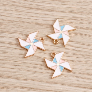 Detail view of colorful enamel windmill charms in gold finish on light wood surface