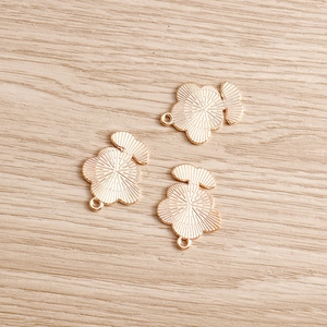 Macro di tre ciondoli a fiore dorati con trama radiale e anellini per gioielli fai-da-te