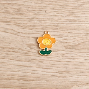 Dettaglio del ciondolo a fiore in smalto arancione e giallo con faccina per gioielli DIY