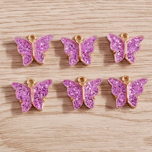 Detailed view of six purple glitter butterfly pendants with gold outlines for DIY jewelry