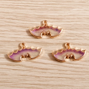 Detailed macro view of three purple gradient bat wing charms with gold metal frames