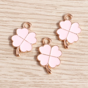 Gros plan de breloques trèfle en émail rose avec bords en or rose pour bijoux DIY