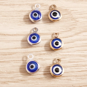 DIY Evil Eye charm pendants in gold and silver finish on a wooden background