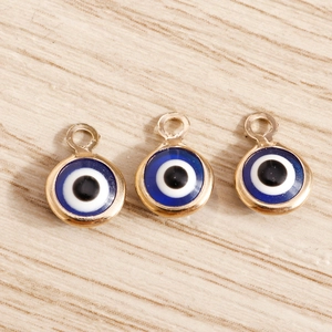 Detailed macro view of three golden evil eye charms on a light wood texture background