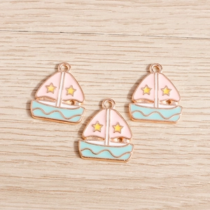 Close-up of pink and blue enamel sailboat charms with gold stars for DIY jewelry