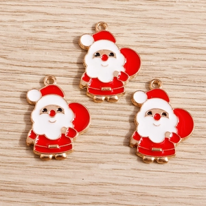 Détail de trois breloques Père Noël en émail avec bordure dorée sur fond en bois clair
