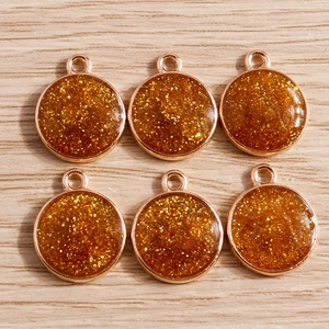 Detail of round gold glitter resin pendants with metal loops for DIY jewelry making