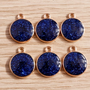 Detail shot of six round golden alloy charms with dark blue glitter filling for DIY jewelry