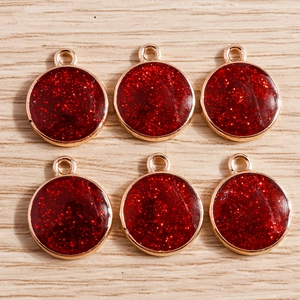 Detail of circular red glitter alloy pendants with gold frames for DIY jewelry making