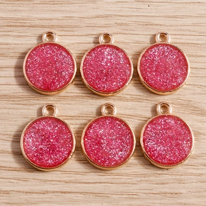 Close-up of rose gold circular pendants with shiny pink glitter for DIY jewelry making