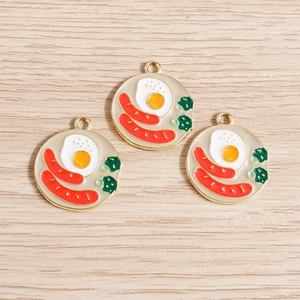 Detailed macro view of enamel breakfast pendants with fried egg and sausage for DIY jewelry