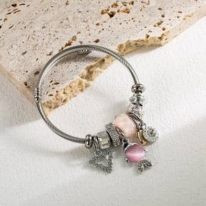 Détail du bracelet torsadé argenté avec des perles en verre roses et charmes en cristal