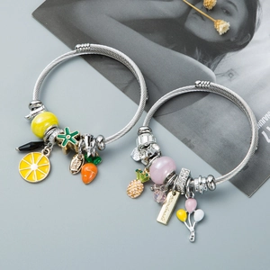 Close-up of silver steel wire bracelets with pineapple, lemon, and handmade charms