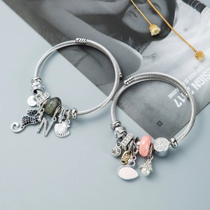 Close-up of silver swan and seahorse charms on adjustable twisted wire bracelets