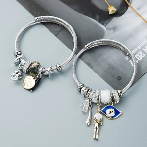 Detail of silver wire rope bracelets featuring heart charms and blue evil eye beads