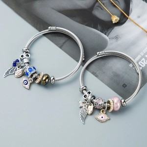 Detail shot of Evil Eye and wing charms on adjustable wire bracelets with glazed beads