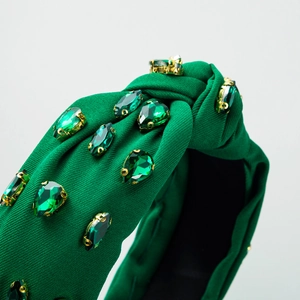 Dark green knotted headband featuring elegant emerald gemstones and gold-tone settings